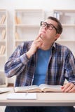 Il giovane studente che prepara agli esami della scuola con i libri Fotografia Stock Libera da Diritti Il giovane studente che prepara agli esami della scuola con i libri Fotografia Stock Libera da Diritti