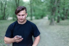 Il giovane uomo caucasico esamina lo schermo del telefono cellulare fotografia stock Il giovane uomo caucasico esamina lo schermo del telefono cellulare fotografia stock