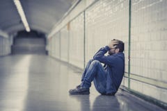 Il giovane uomo malato ha perso la depressione di sofferenza che si siede sul tunnel a terra del sottopassaggio della via Il giovane uomo malato ha perso la depressione di sofferenza che si siede sul tunnel a terra del sottopassaggio della via