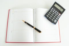 Il libro quotidiano di piano si è sparso fuori con una penna stilografica e un calcolatore su fotografia stock Il libro quotidiano di piano si è sparso fuori con una penna stilografica e un calcolatore su fotografia stock
