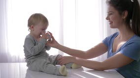 Il neonato sveglio con gli strappi in occhi che beve l'acqua pura da vetro dalle mani della madre e si rallegra nell'estinzione d stock footage Il neonato sveglio con gli strappi in occhi che beve l'acqua pura da vetro dalle mani della madre e si rallegra nell'estinzione d stock footage