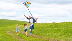 Il padre ed i bambini felici della famiglia funzionano con l'aquilone sul prato fotografie stock Il padre ed i bambini felici della famiglia funzionano con l'aquilone sul prato fotografie stock