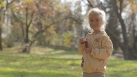 Il piccolo colpo biondo sveglio della ragazza bolle in parco video d archivio Il piccolo colpo biondo sveglio della ragazza bolle in parco video d archivio