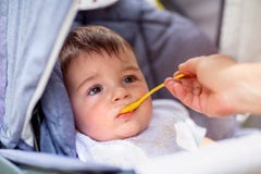 Il piccolo neonato sta mangiando mentre si sedeva in una carrozzina fotografia stock libera da diritti Il piccolo neonato sta mangiando mentre si sedeva in una carrozzina fotografia stock libera da diritti