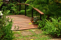 Il ponte di legno sopra lo stagno con il giardino floreale fotografia stock libera da diritti Il ponte di legno sopra lo stagno con il giardino floreale fotografia stock libera da diritti