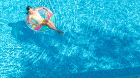 Il punto di vista aereo del fuco della bambina nella piscina da sopra, nuotate del bambino sulla ciambella gonfiabile dell'anello fotografie stock Il punto di vista aereo del fuco della bambina nella piscina da sopra, nuotate del bambino sulla ciambella gonfiabile dell'anello fotografie stock