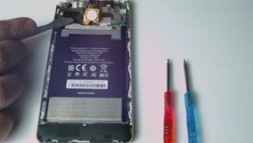 Il punto di vista alto vicino della tenuta maschio della mano ha utilizzato la batteria del telefono per riparare e sostituire il Il punto di vista alto vicino della tenuta maschio della mano ha utilizzato la batteria del telefono per riparare e sostituire il