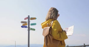 Il punto di vista posteriore della viandante femminile caucasica in impermeabile giallo sta nelle montagne con una mappa a dispos video d archivio Il punto di vista posteriore della viandante femminile caucasica in impermeabile giallo sta nelle montagne con una mappa a dispos video d archivio