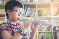 Il ragazzo che gioca il clarinetto, suona la tromba a casa, soffiando una flauto dolce immagine stock libera da diritti Il ragazzo che gioca il clarinetto, suona la tromba a casa, soffiando una flauto dolce immagine stock libera da diritti