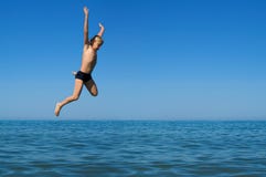 Il ragazzo che salta nel mare fotografie stock libere da diritti Il ragazzo che salta nel mare fotografie stock libere da diritti