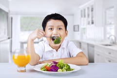 Ragazzo che mangia broccolo a casa fotografia stock Ragazzo che mangia broccolo a casa fotografia stock