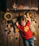 Il ragazzo sveglio del piccolo bambino sta preparando per l'autunno Il bambino si trova mettendo le mani dietro la testa e riposa fotografie stock Il ragazzo sveglio del piccolo bambino sta preparando per l'autunno Il bambino si trova mettendo le mani dietro la testa e riposa fotografie stock