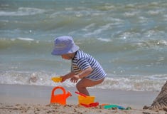 Il ragazzo sveglio gioca un secchio sulla spiaggia immagini stock libere da diritti Il ragazzo sveglio gioca un secchio sulla spiaggia immagini stock libere da diritti