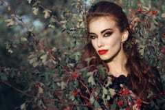 Il ritratto della donna redheaded sciccosa con provocatorio compone la condizione nel cespuglio della bacca e lo sguardo diritto immagine stock libera da diritti Il ritratto della donna redheaded sciccosa con provocatorio compone la condizione nel cespuglio della bacca e lo sguardo diritto immagine stock libera da diritti