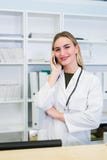 Il ritratto di bello infermiere sorridente alla stazione dello scrittorio mentre parla sul telefono e completare un formulario in immagine stock libera da diritti Il ritratto di bello infermiere sorridente alla stazione dello scrittorio mentre parla sul telefono e completare un formulario in immagine stock libera da diritti