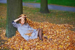 Il ritratto di giovane ragazza attraente con giallo lascia in suoi capelli sul fondo di autunno Fotografia Stock Libera da Diritti Il ritratto di giovane ragazza attraente con giallo lascia in suoi capelli sul fondo di autunno Fotografia Stock Libera da Diritti