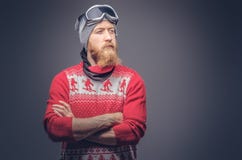 Il ritratto di un maschio barbuto della testarossa brutale in un cappello dell'inverno con i vetri di protezione si è vestito in immagini stock Il ritratto di un maschio barbuto della testarossa brutale in un cappello dell'inverno con i vetri di protezione si è vestito in immagini stock