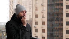 Il tipo con la barba sta stando sul balcone che fuma una sigaretta stock footage Il tipo con la barba sta stando sul balcone che fuma una sigaretta stock footage