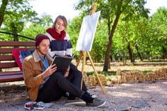 Il tipo e la ragazza stanno guardando le immagini nel loro album per disegnare immagini stock Il tipo e la ragazza stanno guardando le immagini nel loro album per disegnare immagini stock