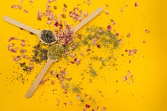 Il tè è aumentato, camomilla e timo in un cucchiaio di legno su un fondo giallo fotografia stock Il tè è aumentato, camomilla e timo in un cucchiaio di legno su un fondo giallo fotografia stock