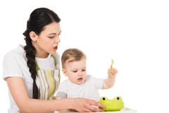 ilsken moder i förklädet som försöker att mata den lilla sonen som sitter i highchair fotografering för bildbyråer ilsken moder i förklädet som försöker att mata den lilla sonen som sitter i highchair fotografering för bildbyråer