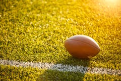 Image of ball for American football lying on green field on summer