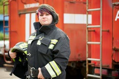 Image of brunette firefighter standing next to firefighters car.