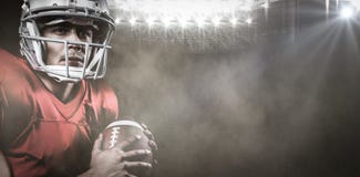 Image composée du joueur de football américain sérieux semblant parti tout en tenant la boule photographie stock libre de droits Image composée du joueur de football américain sérieux semblant parti tout en tenant la boule photographie stock libre de droits