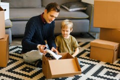 Image de père et de fils heureux avec le microscope se reposant sur le plancher parmi des boîtes en carton photo libre de droits Image de père et de fils heureux avec le microscope se reposant sur le plancher parmi des boîtes en carton photo libre de droits
