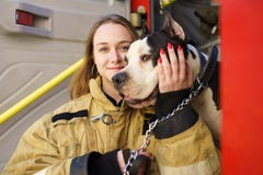 Image of happy firewoman with dog standing near fire truck