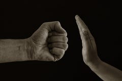 Image of male fist and female hand showing STOP. Domestic violence concept against women. Black and white photo.