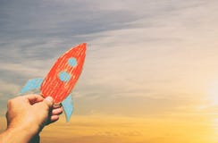 Image of male hand holding a rocket against the sky. imagination and success concept. stock photo Image of male hand holding a rocket against the sky. imagination and success concept. stock photo