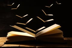 image of open antique book over wooden table with flying pages. Stock Images image of open antique book over wooden table with flying pages. Stock Images