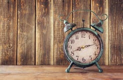 Image of vintage alarm clock on wooden table in front of wooden background. retro filtered Stock Image Image of vintage alarm clock on wooden table in front of wooden background. retro filtered Stock Image