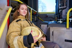 Image of woman firefighter with helmet in hands sitting in fire truck