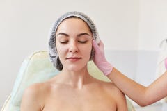 A imagem do cosmetologist sem cara em luvas médicas cor-de-rosa no trabalho no salão de beleza da cosmetologia examina a mulher a foto de stock A imagem do cosmetologist sem cara em luvas médicas cor-de-rosa no trabalho no salão de beleza da cosmetologia examina a mulher a foto de stock
