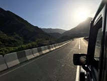 A imagem na frente da cena do carro de esportes atrás como o sol que vai para baixo com as turbinas eólicas na parte traseira ilustração stock A imagem na frente da cena do carro de esportes atrás como o sol que vai para baixo com as turbinas eólicas na parte traseira ilustração stock