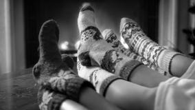 Imagen blanco y negro de la familia que lleva los calcetines de lana hechos punto que se relajan por la chimenea foto de archivo libre de regalías Imagen blanco y negro de la familia que lleva los calcetines de lana hechos punto que se relajan por la chimenea foto de archivo libre de regalías