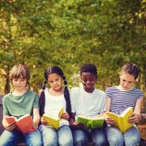 Imagen compuesta de los libros de lectura de los niños en el parque imágenes de archivo libres de regalías Imagen compuesta de los libros de lectura de los niños en el parque imágenes de archivo libres de regalías
