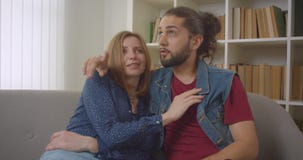 Imagen de un joven novio caucásico sentado en el sofá hablando alegremente entre ellos almacen de video Imagen de un joven novio caucásico sentado en el sofá hablando alegremente entre ellos almacen de video