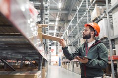Immagazzini il responsabile che controlla il suo inventario in un grande magazzino immagine stock libera da diritti Immagazzini il responsabile che controlla il suo inventario in un grande magazzino immagine stock libera da diritti