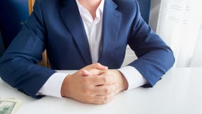 Immagine del primo piano di riuscito uomo d'affari ricco in vestito blu che si siede con le mani piegate all'ufficio moderno fotografie stock libere da diritti Immagine del primo piano di riuscito uomo d'affari ricco in vestito blu che si siede con le mani piegate all'ufficio moderno fotografie stock libere da diritti