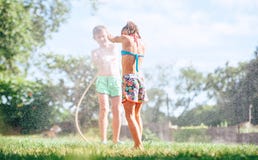 Immagine felice di concetto di infanzia Due childs che giocano nel giardino, si versa dal tubo flessibile, fa una pioggia fotografia stock Immagine felice di concetto di infanzia Due childs che giocano nel giardino, si versa dal tubo flessibile, fa una pioggia fotografia stock