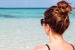 Immagine quarta tre di una giovane donna sulla spiaggia che esamina il chiaro mare blu immagini stock Immagine quarta tre di una giovane donna sulla spiaggia che esamina il chiaro mare blu immagini stock