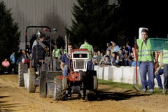 Impulsiones de un hombre joven en un tirón del tractor del césped imágenes de archivo libres de regalías Impulsiones de un hombre joven en un tirón del tractor del césped imágenes de archivo libres de regalías
