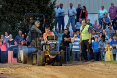 Impulsiones de un hombre joven en un tirón del tractor del césped imágenes de archivo libres de regalías Impulsiones de un hombre joven en un tirón del tractor del césped imágenes de archivo libres de regalías