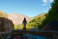 Incrocio turistico femminile un ponte ombreggiato nelle montagne di atlante fotografia stock libera da diritti Incrocio turistico femminile un ponte ombreggiato nelle montagne di atlante fotografia stock libera da diritti