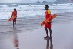 India, GOA, January 28, 2018. Men rescuers walk along the shore in red clothes, whistle in the whistle, warn of danger in the sea stock photos India, GOA, January 28, 2018. Men rescuers walk along the shore in red clothes, whistle in the whistle, warn of danger in the sea stock photos