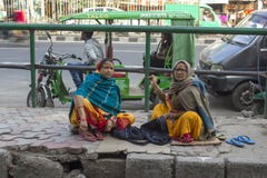 Indian adult women sew clothes sitting on the sidewalk against the backdrop of urban traffic royalty free stock photography Indian adult women sew clothes sitting on the sidewalk against the backdrop of urban traffic royalty free stock photography