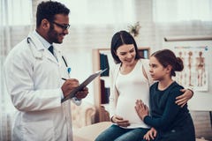 Indian doctor seeing patients in office. Pregnant woman with daughter. stock photography Indian doctor seeing patients in office. Pregnant woman with daughter. stock photography